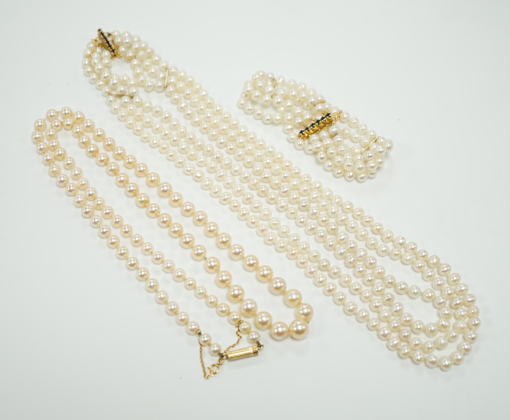 Two Cultured pearl necklaces including a triple strand with yellow metal and sapphire set clasp, 46cm and a matching bracelet.